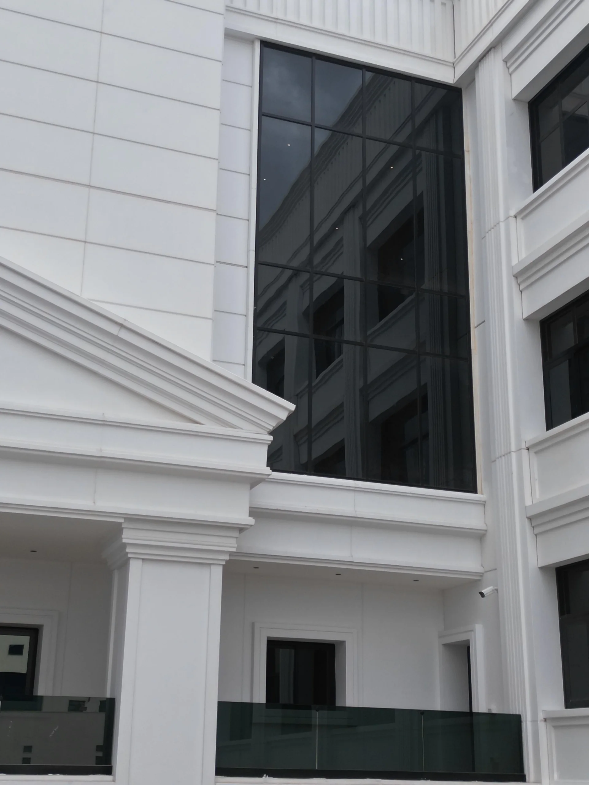 Giriş portikosu üstü neoklasik üçgen alınlık, cam parapet ve cephe camları